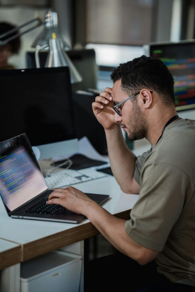pexels-photo-12903271-12903271 A man intensely focused on coding at a desk in a modern office environment.